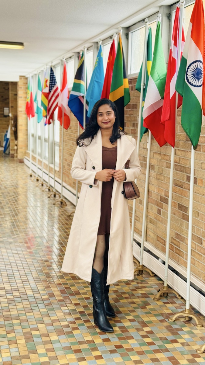 Sruthi Gade standing in a hallway with international flags